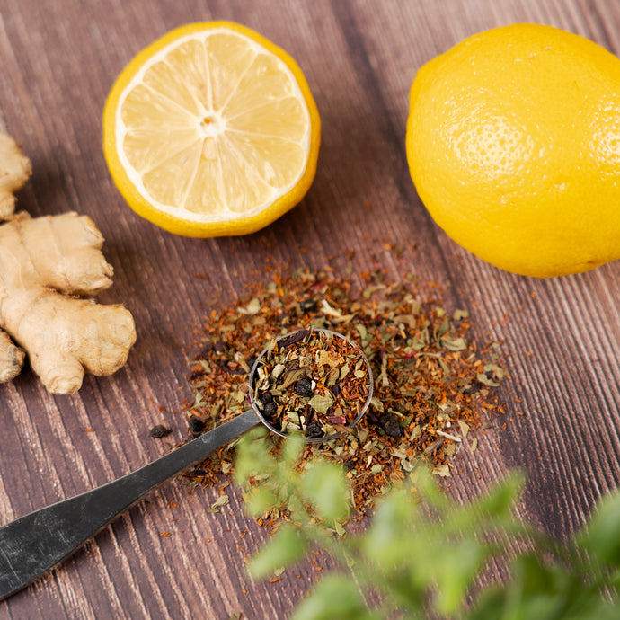 Immunity blend in a spoon with lemons and ginger on a wooden surface