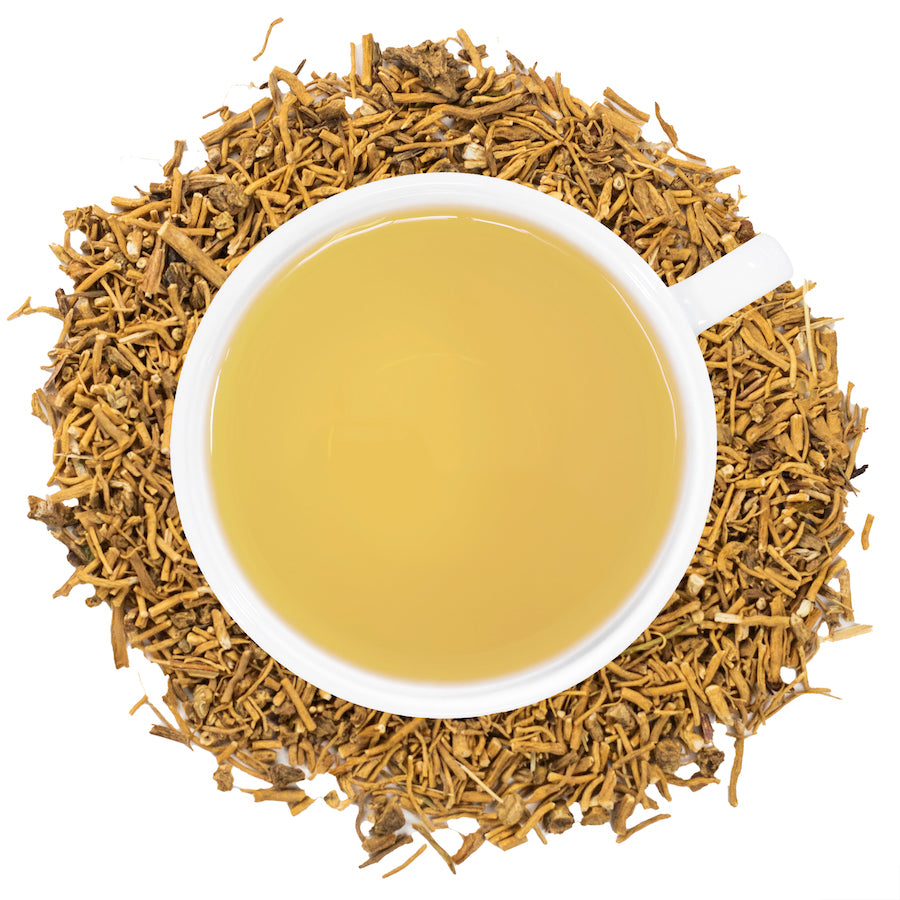 A white mug filled with valerian root tea surrounded by valerian root